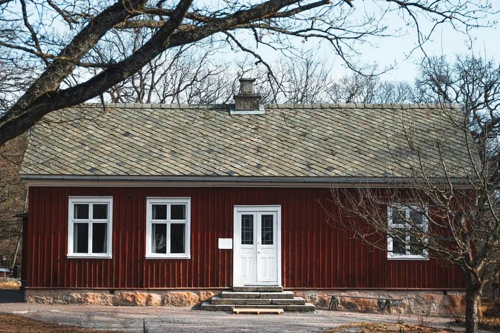 Rødmalt trehus med hvite vinduer og dobbel inngangsdør